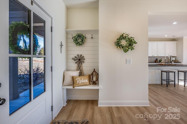 mudroom with recessed lighting, light wood-type flooring, a sink, and baseboards