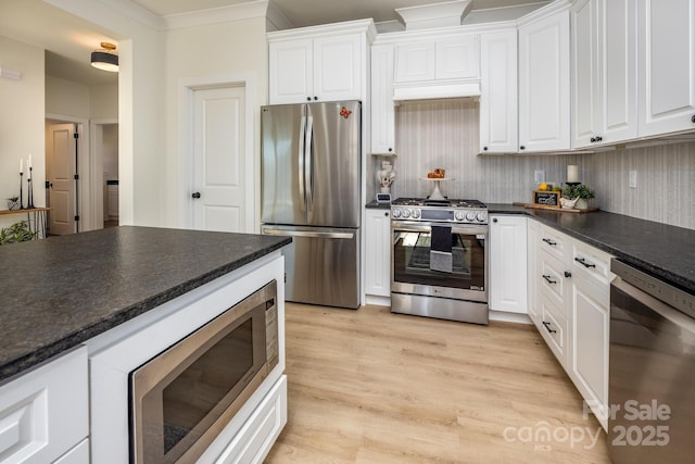 kitchen featuring appliances with stainless steel finishes, tasteful backsplash, white cabinets, light hardwood / wood-style floors, and crown molding