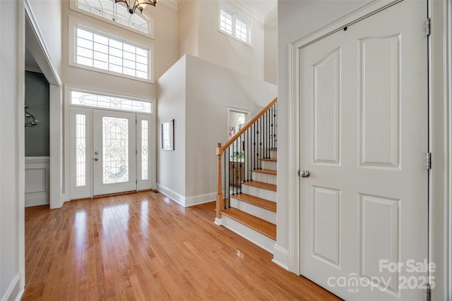 foyer featuring crown molding, light hardwood / wood-style floors, and a high ceiling