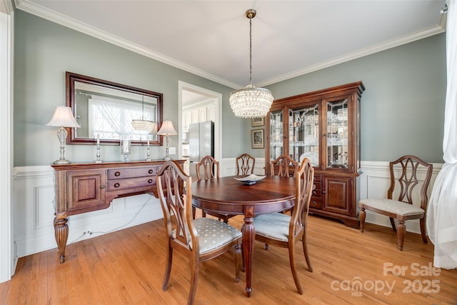 dining space featuring a notable chandelier, light hardwood / wood-style flooring, and ornamental molding