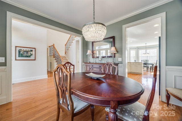 dining area featuring crown molding, a chandelier, and light wood-type flooring