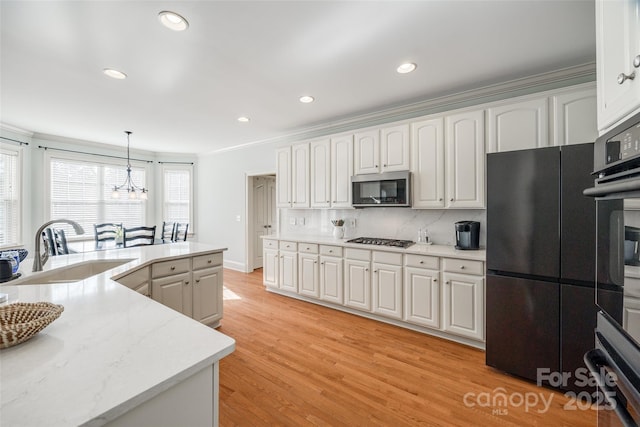 kitchen with pendant lighting, appliances with stainless steel finishes, sink, and white cabinets