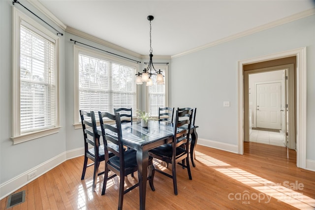 dining area with an inviting chandelier, light hardwood / wood-style flooring, ornamental molding, and plenty of natural light