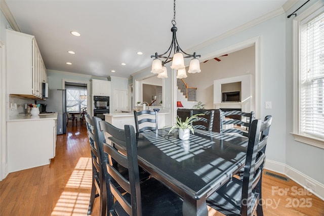 dining area featuring ornamental molding, a healthy amount of sunlight, and light hardwood / wood-style floors