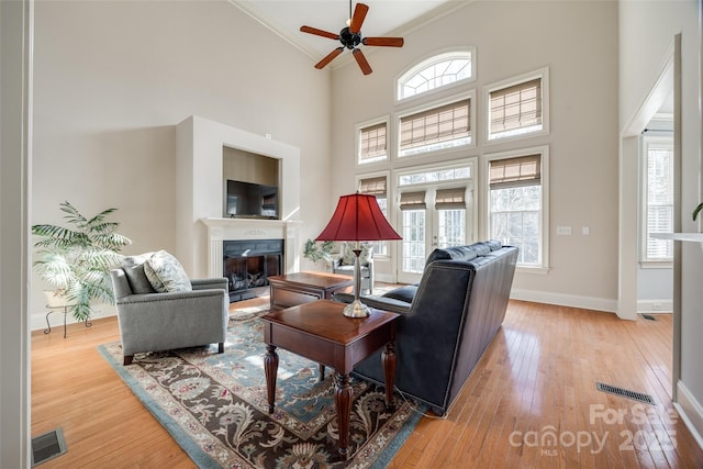 living room with crown molding, a healthy amount of sunlight, light hardwood / wood-style flooring, and french doors