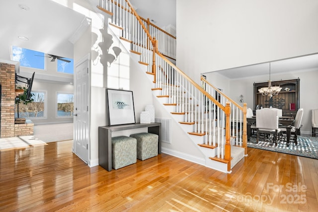 stairway featuring a high ceiling, hardwood / wood-style flooring, an inviting chandelier, and ornamental molding