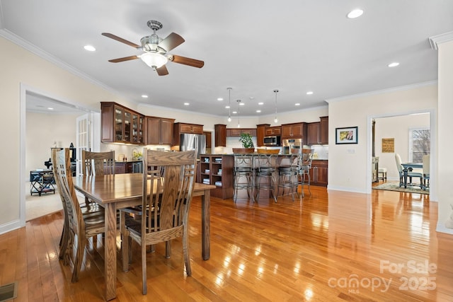 dining area featuring ceiling fan, light wood-type flooring, and crown molding