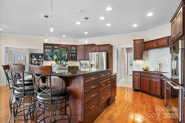 kitchen with stainless steel fridge, tasteful backsplash, dark stone counters, pendant lighting, and a kitchen island