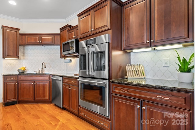 kitchen with appliances with stainless steel finishes, dark stone counters, tasteful backsplash, and ornamental molding