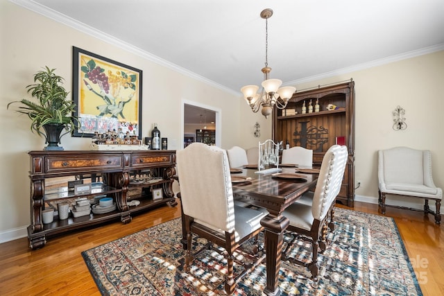 dining area featuring crown molding, hardwood / wood-style floors, and an inviting chandelier