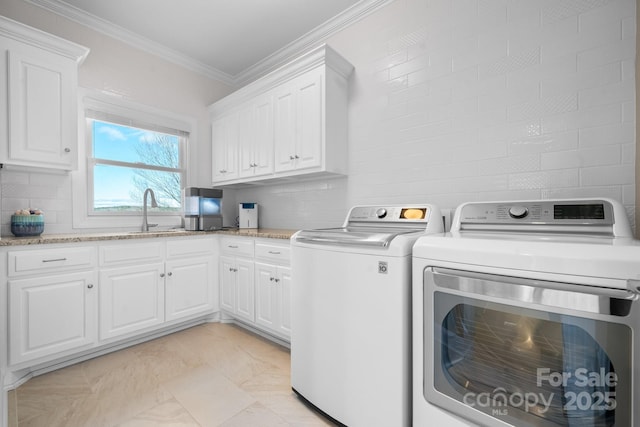 clothes washing area with cabinets, washer and dryer, crown molding, and sink