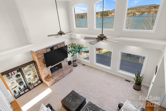 carpeted living room with ceiling fan and a brick fireplace