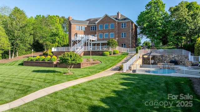 rear view of property featuring fence, stairway, an outdoor pool, a chimney, and a yard
