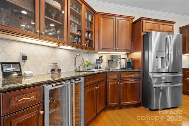 kitchen featuring wine cooler, dark stone counters, stainless steel fridge with ice dispenser, a sink, and light wood-style flooring