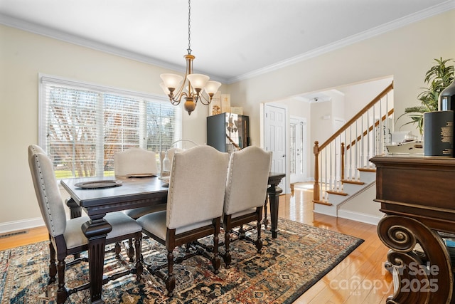 dining area with visible vents, ornamental molding, wood finished floors, and a chandelier