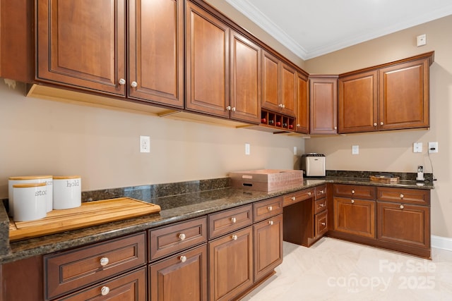 kitchen featuring ornamental molding, dark stone countertops, and brown cabinets