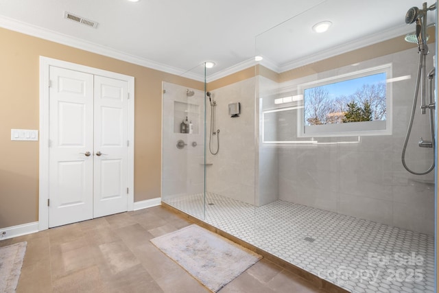bathroom with crown molding, baseboards, visible vents, and a tile shower