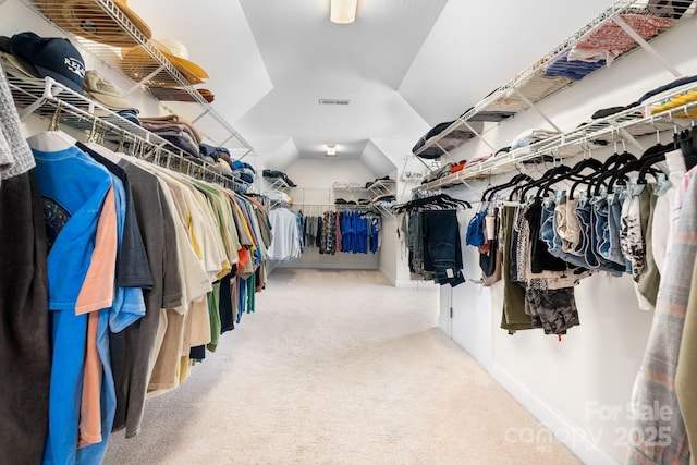 walk in closet featuring visible vents, carpet, and vaulted ceiling