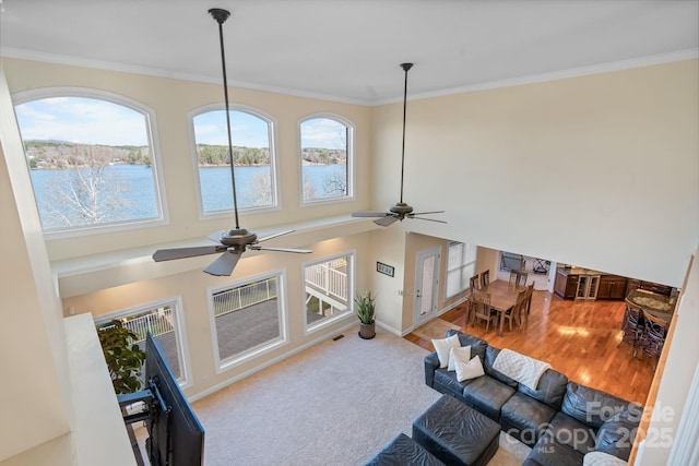 living room with ceiling fan, visible vents, crown molding, baseboards, and a water view