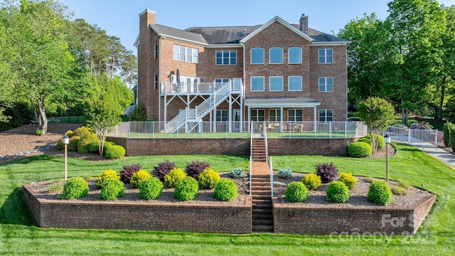 rear view of property featuring stairway, a lawn, fence, and a chimney