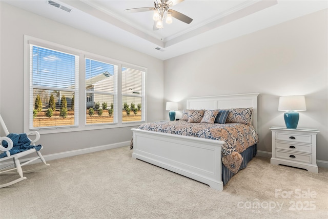 carpeted bedroom with ceiling fan, crown molding, and a tray ceiling