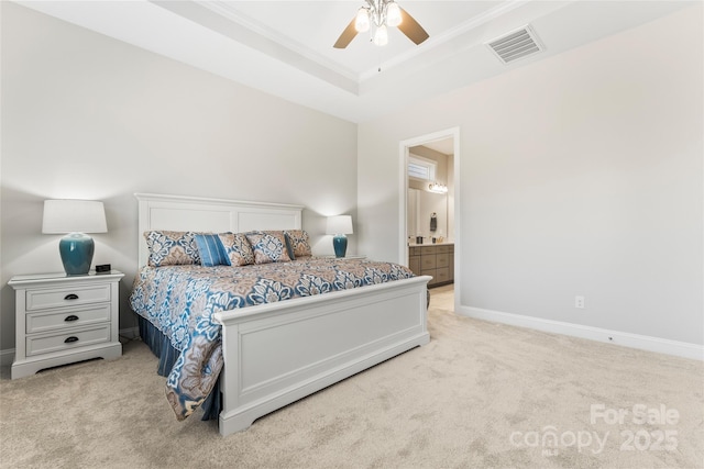 carpeted bedroom with ensuite bath, ceiling fan, a tray ceiling, and ornamental molding