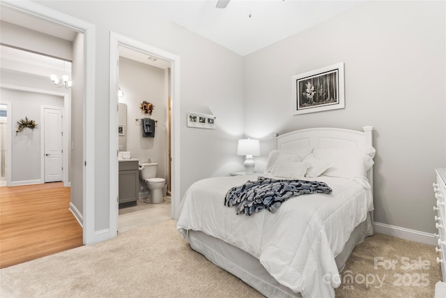 carpeted bedroom featuring ensuite bath and ceiling fan with notable chandelier