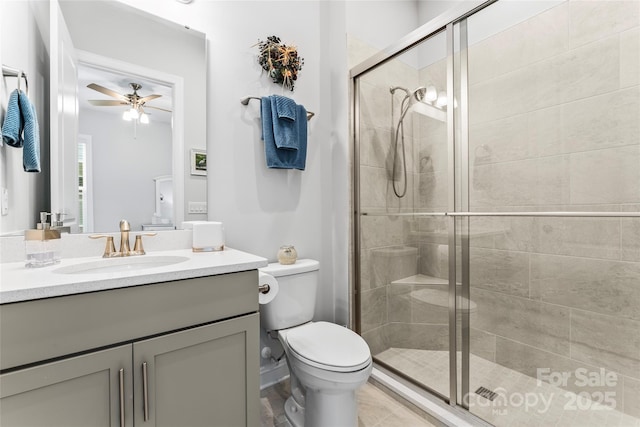 bathroom with ceiling fan, an enclosed shower, vanity, and toilet