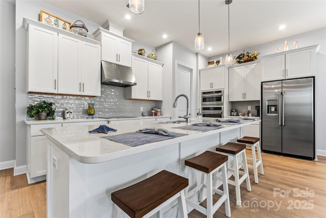 kitchen with appliances with stainless steel finishes, white cabinetry, and a center island with sink