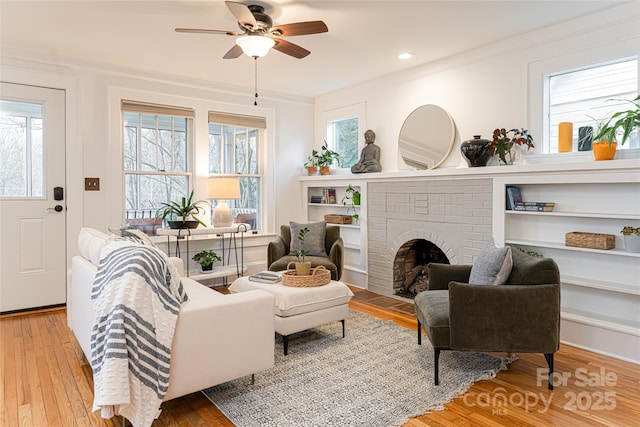 living room featuring ceiling fan, a brick fireplace, a wealth of natural light, and light hardwood / wood-style floors