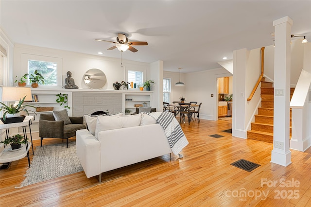 living room with ceiling fan, plenty of natural light, light hardwood / wood-style flooring, and a fireplace