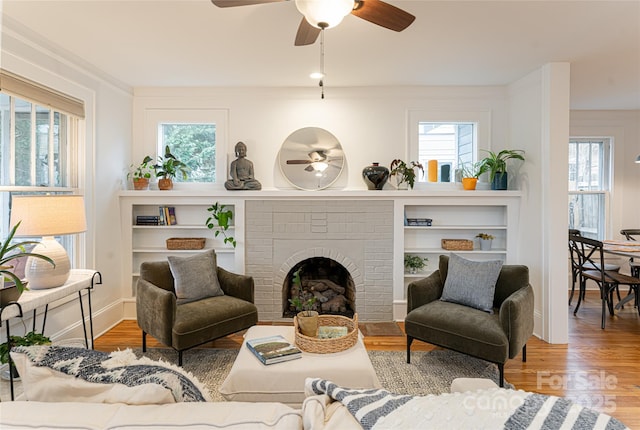 living room with ceiling fan, a fireplace, and hardwood / wood-style flooring