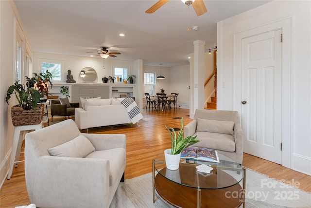 living room with ceiling fan, a fireplace, and light wood-type flooring