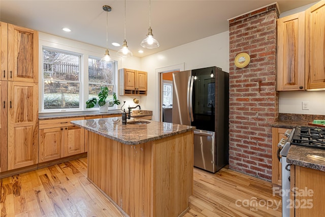 kitchen featuring hanging light fixtures, light wood-type flooring, appliances with stainless steel finishes, and a kitchen island