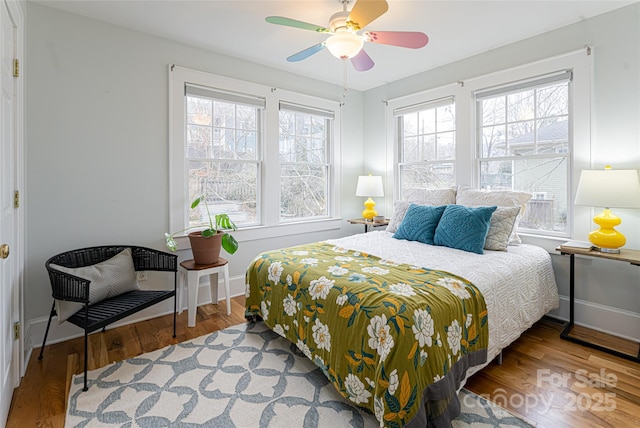 bedroom featuring ceiling fan, multiple windows, and hardwood / wood-style floors