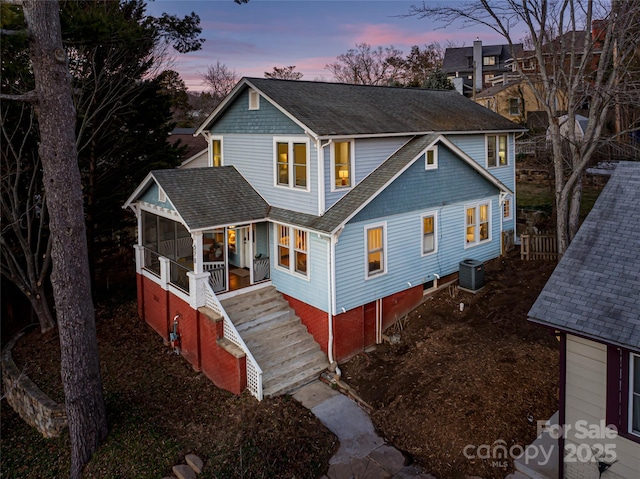 view of front of home with central air condition unit and a sunroom