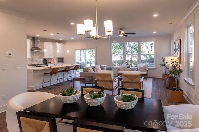 dining space featuring dark hardwood / wood-style floors, ornamental molding, and ceiling fan with notable chandelier