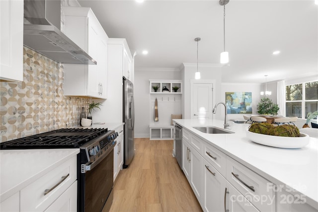 kitchen featuring stainless steel appliances, a sink, white cabinetry, light countertops, and wall chimney range hood