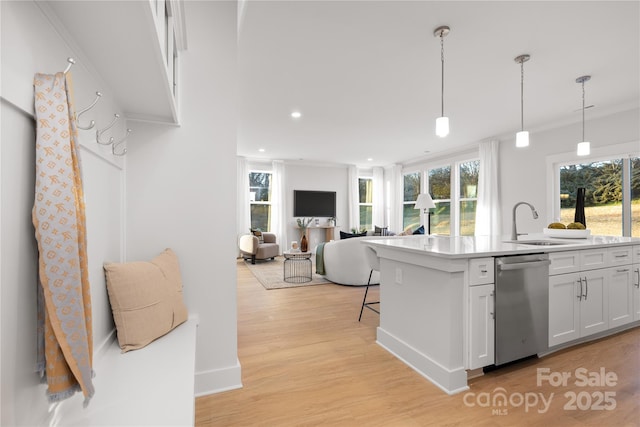 kitchen featuring light wood-style flooring, light countertops, white cabinetry, pendant lighting, and stainless steel dishwasher