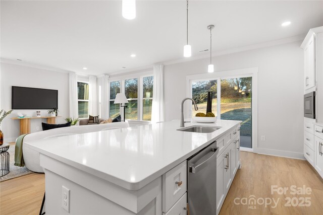 kitchen featuring a kitchen island with sink, stainless steel appliances, a sink, open floor plan, and light wood finished floors