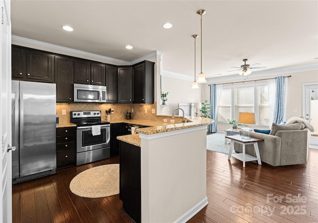 kitchen featuring decorative light fixtures, ornamental molding, kitchen peninsula, and appliances with stainless steel finishes