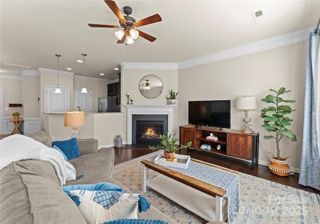 living room featuring ceiling fan, ornamental molding, and dark hardwood / wood-style floors