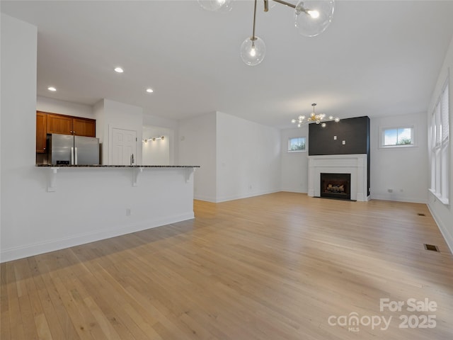 unfurnished living room featuring light wood-type flooring and an inviting chandelier