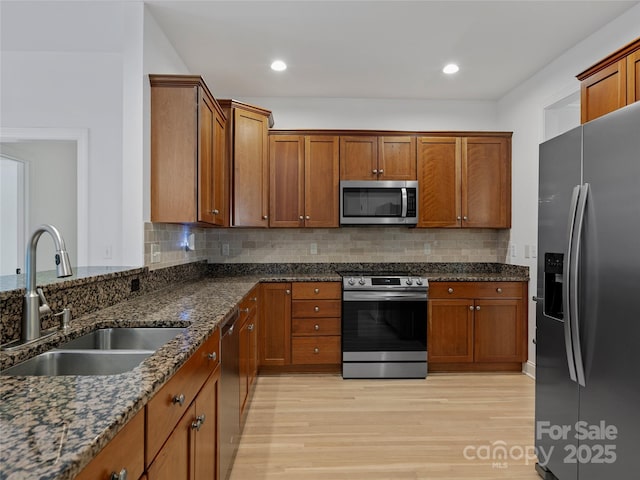 kitchen featuring stainless steel appliances, dark stone counters, tasteful backsplash, and sink