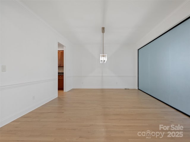 spare room with ornamental molding and light wood-type flooring