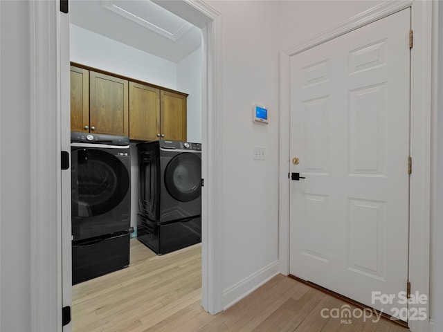 clothes washing area with light hardwood / wood-style flooring, cabinets, and washing machine and dryer