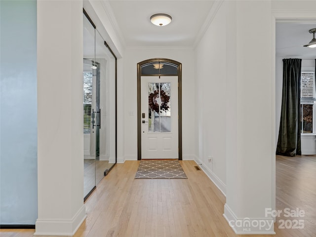 foyer with crown molding and light hardwood / wood-style flooring