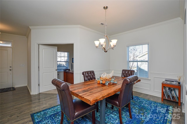 dining space with dark hardwood / wood-style floors, an inviting chandelier, and crown molding