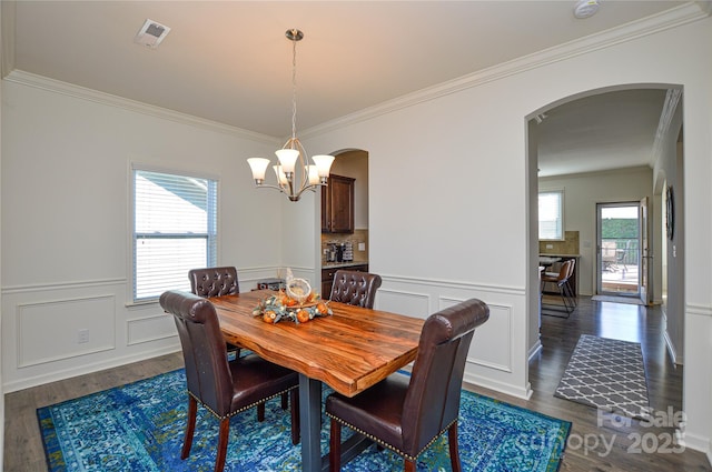 dining area with dark hardwood / wood-style floors, an inviting chandelier, and crown molding