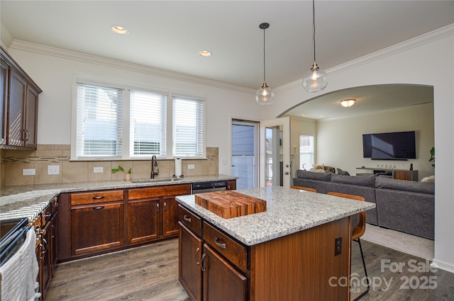 kitchen featuring light stone counters, dark wood-type flooring, sink, pendant lighting, and a kitchen island